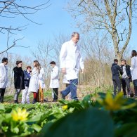 Eine Gruppe von Ärzten und Patienten in Laborkitteln genießt die Zeit im Garten auf dem saftigen Gras.